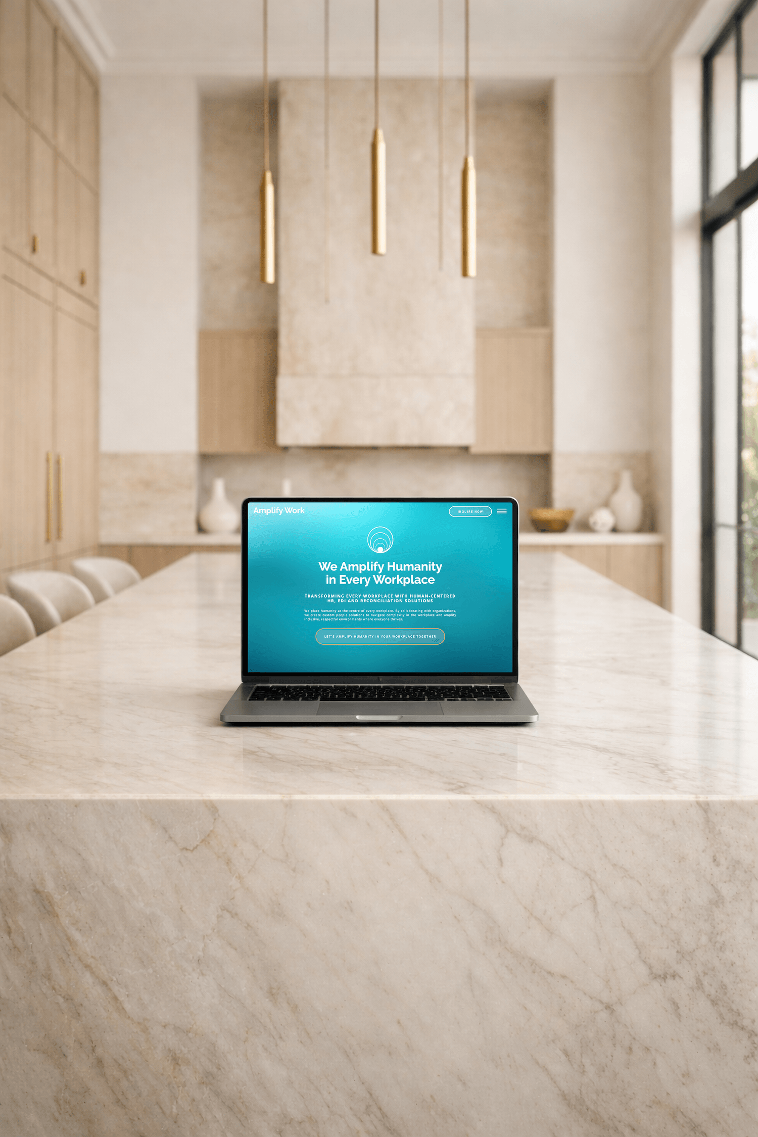 Laptop displaying Amplify Work website on a marble kitchen island in a modern neutral-toned interior