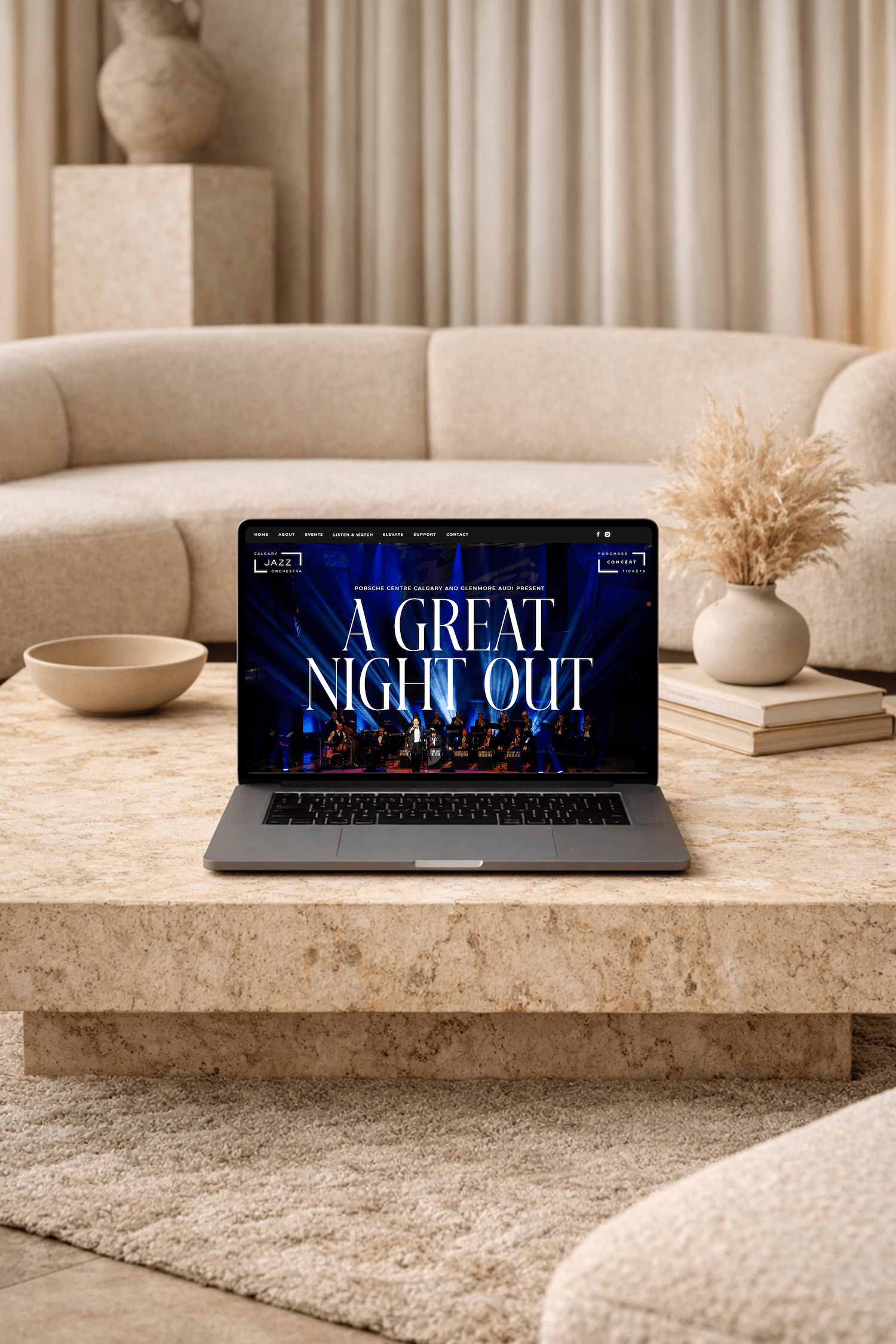 Laptop displaying Calgary Jazz Orchestra website on a stone coffee table in a cozy living room